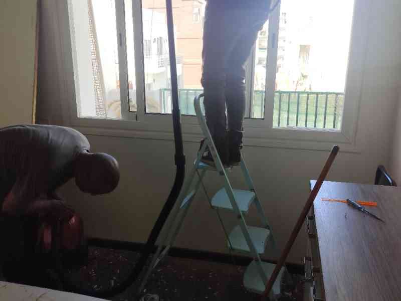 Une scène de travaux de rénovation dans une pièce, un homme est debout sur un escabeau près d'une fenêtre, photo gratuite