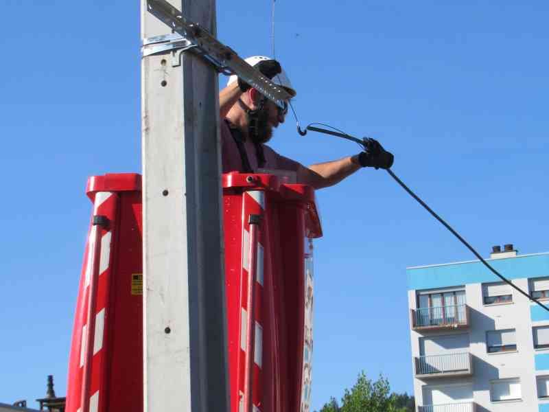 Electricien raccordant des câbles électriques sur une grue rouge