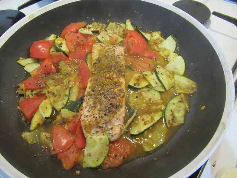 Courgettes et tomates assaisonnées d'épices dans une poêle pavé de saumon