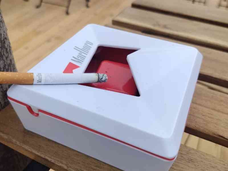 Un cendrier de la marque Marlboro, avec une cigarette Marlboro posée dessus, photo gratuite