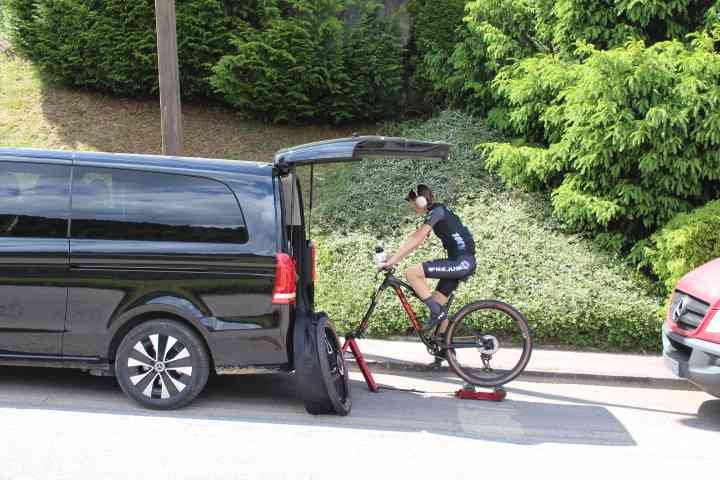 Mercedes-Benz Classe V avec une personne faisant du vélo sur un home trainer à l'arrière du véhicule photo gratuite