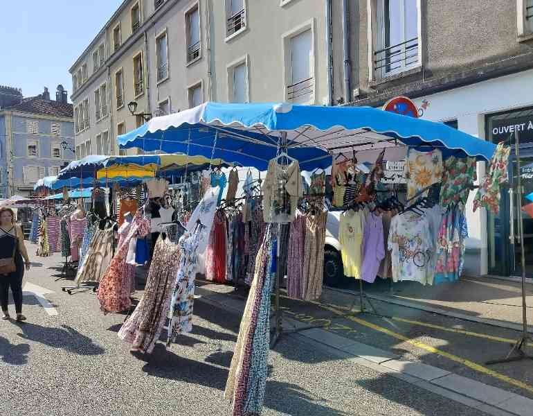 Un marché en plein air, plusieurs stands de vêtements installés le long d'une rue, sous des parasols, photo gratuite