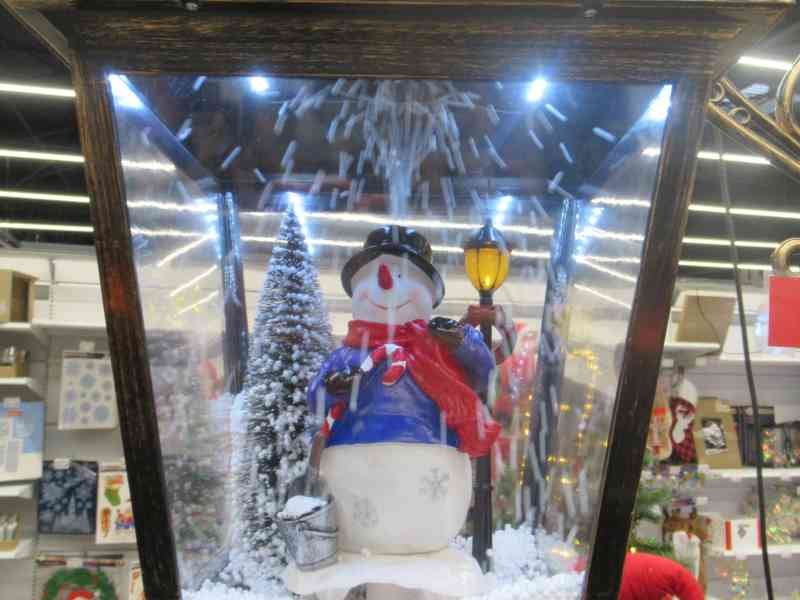 Une lanterne de Noël décorative avec un bonhomme de neige et un effet de chute de neige artificielle, photo gratuite