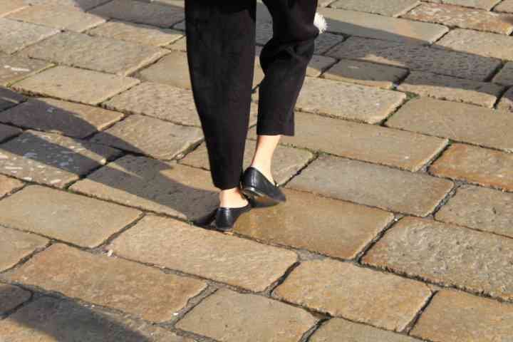 Une personne marchant sur un chemin pavé de dalles de pierre chaussée de chaussures noires plates, photo gratuite