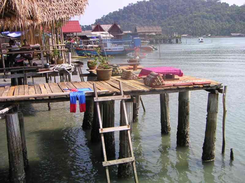 Une terrasse en bois avec des coussins et une échelle menant à l'eau, une construction sur pilotis au-dessus de l'eau, photo gratuite