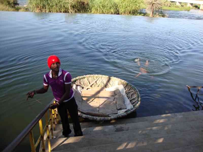 Une personne au bord de l'eau, une petite embarcation ronde et légère, traditionnellement utilisée pour la pêche ou le transport sur les rivières en Inde, photo gratuite