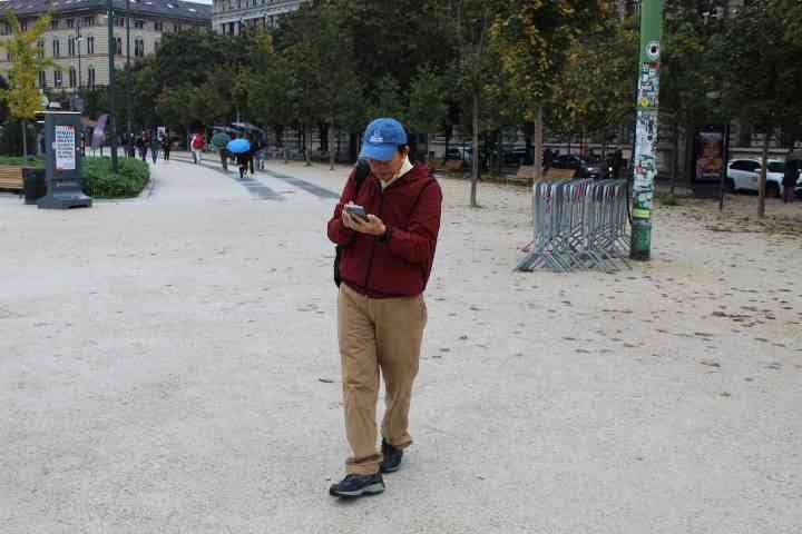 Une personne marchant dans un espace public, un parc, tout en consultant son téléphone portable, photo gratuite