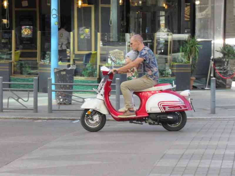 Homme roulant sur un scooter à moteur rouge et blanc