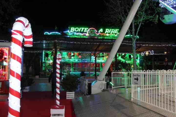 Une attraction de fête foraine nommée "Boîte à Rire", illuminée par des lumières vertes et colorées photo gratuite