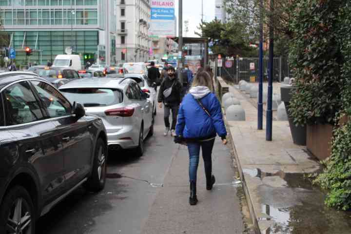 Personnes se baladant sur le trottoir, des voitures stoppées par un feu rouge, dans la ville de Milan Lombardie Italie photo gratuite