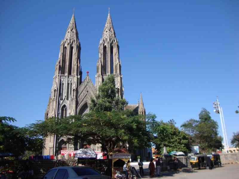 Eglise catholique romaine, Sainte-Philomène de Mysore, une rue animée avec des véhicules et des piétons, ainsi que de la végétation, photo gratuite