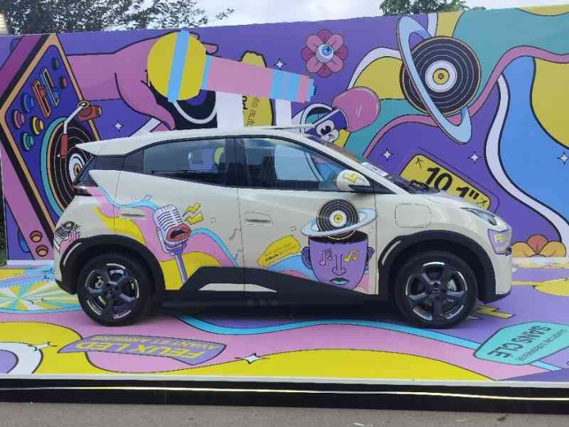 Une BYD Seagull, une petite citadine électrique, devant un mur plein de graffiti, photo gratuite