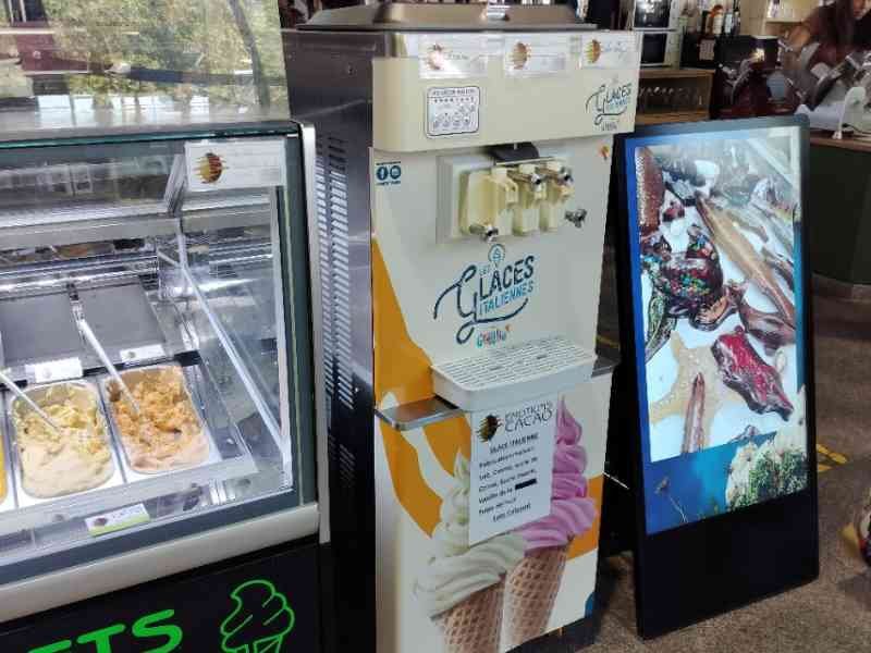Une machine à glaces et une vitrine réfrigérée présentant différentes saveurs de glaces et de sorbets, photo gratuite